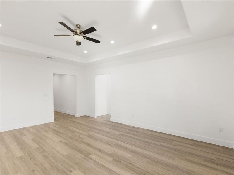 Empty room with recessed lighting, light wood-style flooring, a raised ceiling, and ceiling fan
