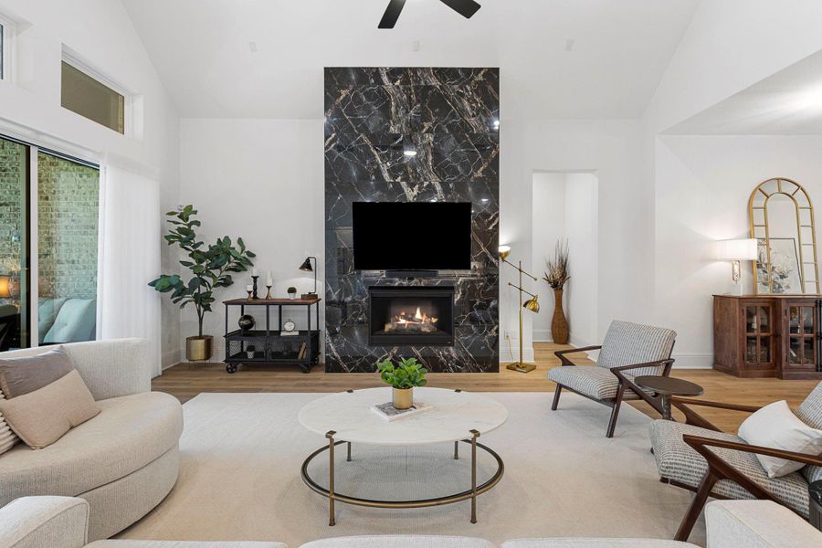 The stunning living room, anchored by a floor-to-ceiling marble fireplace, offers a bright and inviting setting for any occasion.