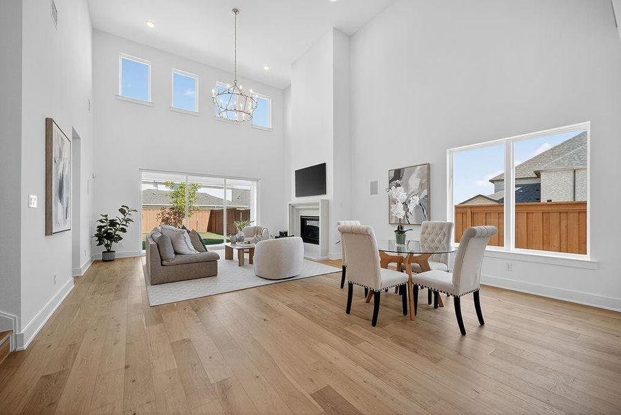 Dining room featuring a glass covered fireplace, light wood-type flooring, healthy amount of natural light, a towering ceiling, and recessed lighting Dining room featuring a glass covered fireplace, light wood-type flooring, healthy amount of natural light, a towering ceiling, and recessed lighting