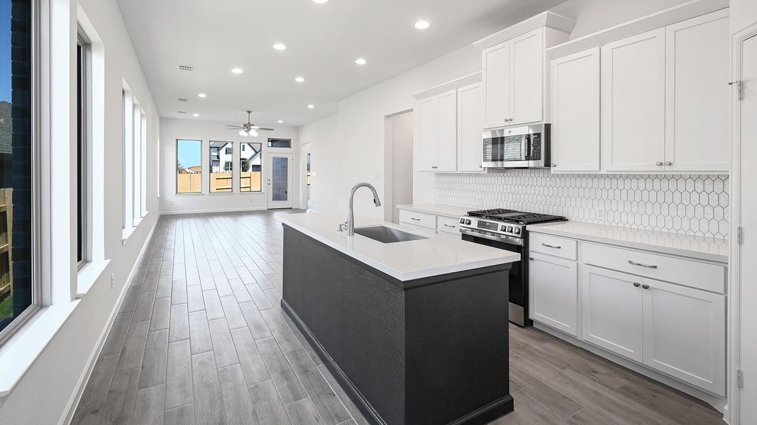 Kitchen with an island with sink, stainless steel appliances, white cabinets, dark wood-style flooring, and recessed lighting Kitchen with an island with sink, stainless steel appliances, white cabinets, dark wood-style flooring, and recessed lighting