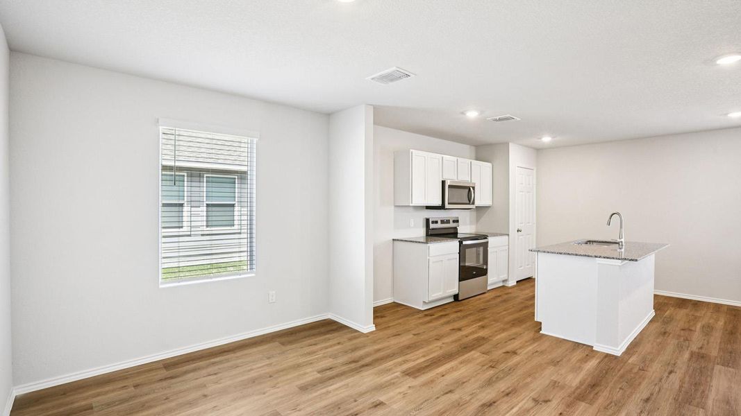 Open-concept living space featuring wood-finish flooring, recessed lighting, and a window with blinds