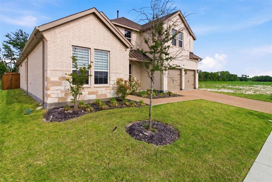 Two-story residence featuring a brick and stone facade, a two-car garage, and a concrete driveway
