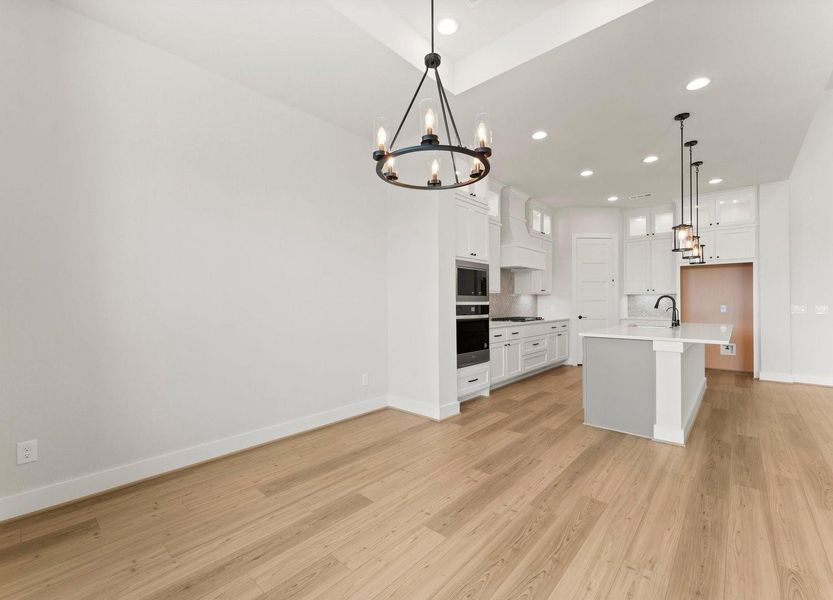 The modern kitchen features light wood flooring,and Elegant light fixtures and recessed lighting add a warm ambiance to the adjoining dining area.