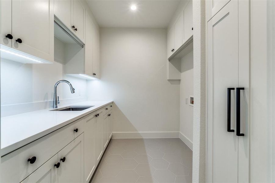 Kitchen with white cabinetry, light tile patterned flooring, and sink