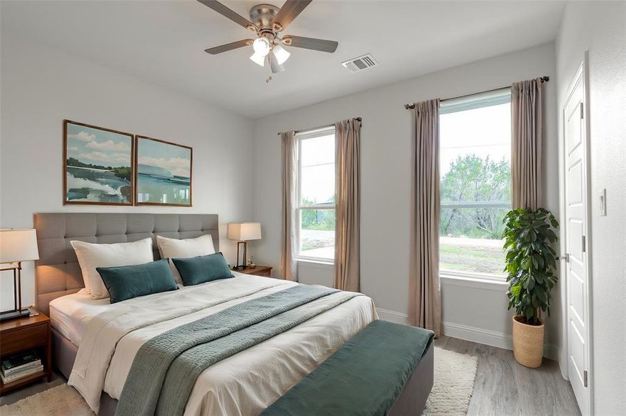 Bedroom with light wood-type flooring, multiple windows, and ceiling fan