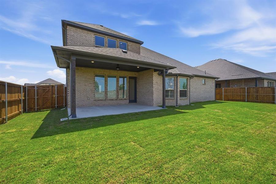 Expansive backyard featuring a manicured lawn, full privacy fencing, and a covered patio with recessed lighting