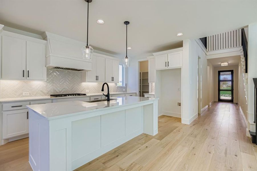 Kitchen featuring light wood-type flooring, tasteful backsplash, decorative light fixtures, light stone counters, and recessed lighting Kitchen featuring light wood-type flooring, tasteful backsplash, decorative light fixtures, light stone counters, and recessed lighting
