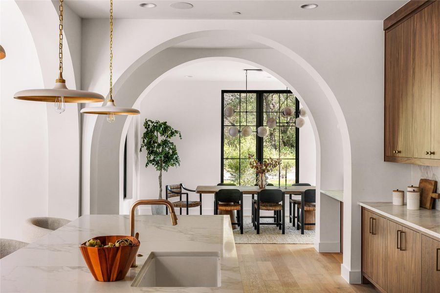 A well-appointed culinary space featuring sleek wood cabinetry and an impressive marble waterfall island.