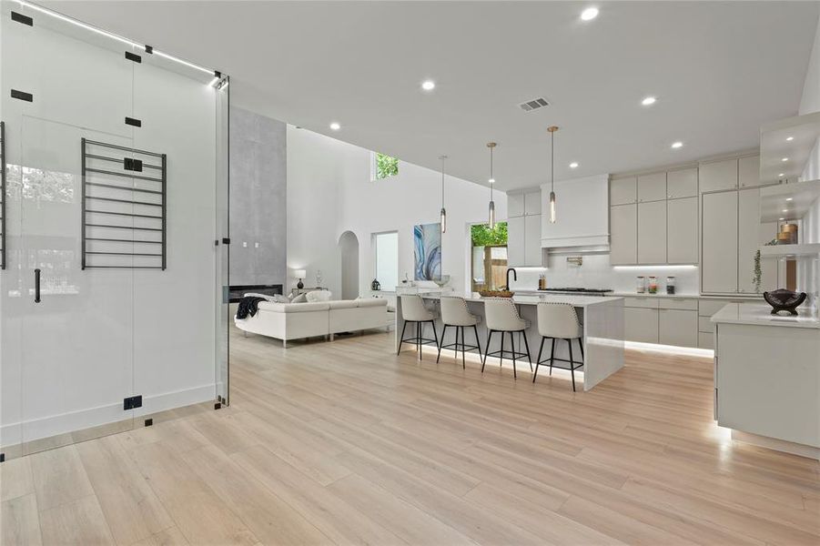 Kitchen with modern cabinets, a breakfast bar, recessed lighting, white cabinets, and a large island