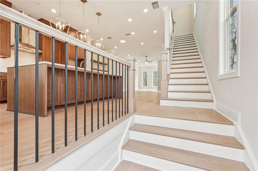 Stairs featuring wood finished floors and hanging lights