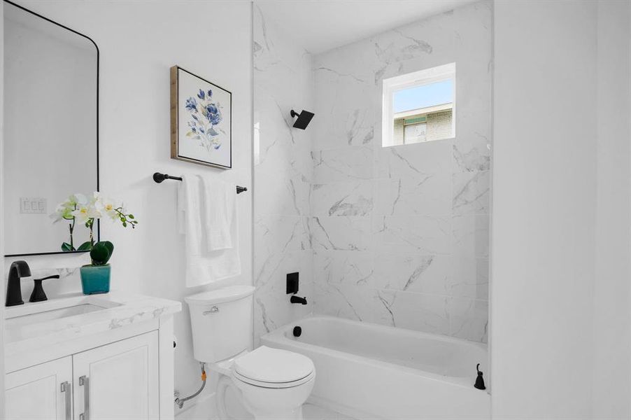 Full bathroom with tiled shower / bath combo, toilet, and vanity