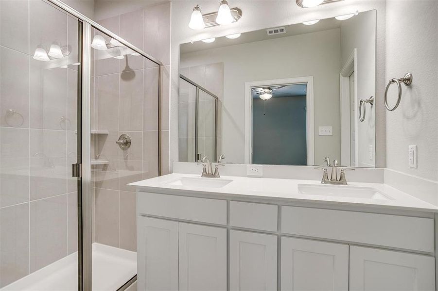 Full bath featuring a stall shower, visible vents, a sink, and double vanity