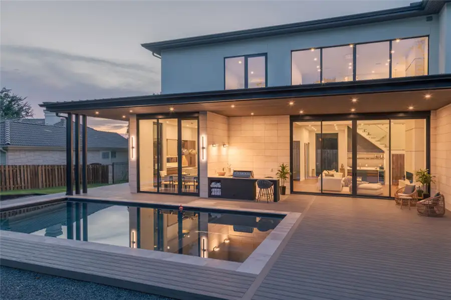 A modern outdoor living space features an in-ground pool and ample patio for entertaining.