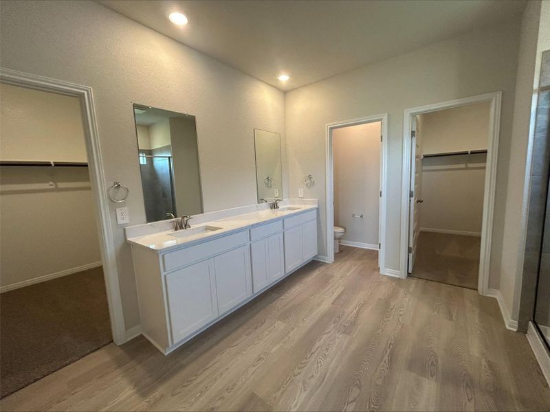 Full bath with a spacious closet, double vanity, a shower stall, wood finished floors, and recessed lighting Full bath with a spacious closet, double vanity, a shower stall, wood finished floors, and recessed lighting