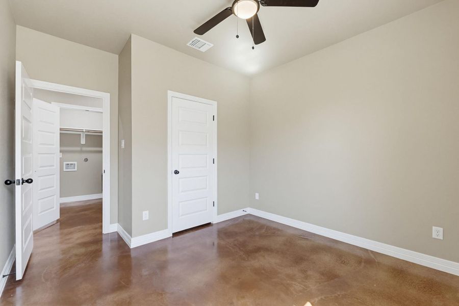 Unfurnished bedroom featuring finished concrete floors, ceiling fan, and a closet