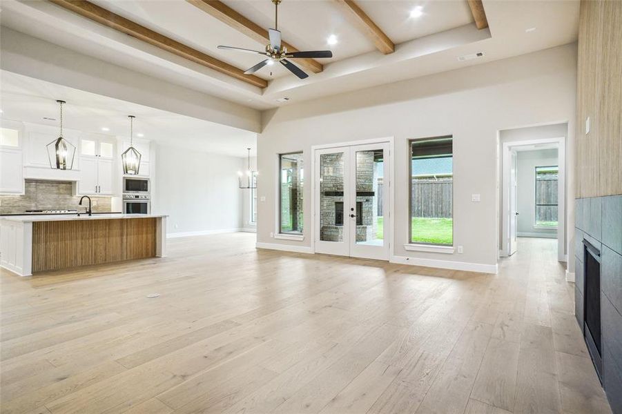 Spacious great room features 13' ceiling with custom stained beams, engineered wood flooring, wall of windows and french doors showcasing the yard and outdoor covered patio! Spacious great room features 13' ceiling with custom stained beams, engineered wood flooring, wall of windows and french doors showcasing the yard and outdoor covered patio!