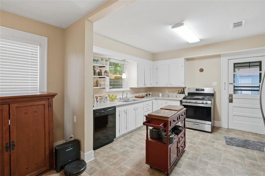 Kitchen featuring white cabinetry, light-toned countertops, a stainless steel gas range, and a black dishwasher