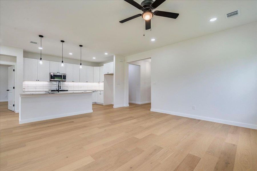 Living area view of the kitchen combines a crisp, white kitchen with a spacious living area featuring warm hardwood floors.