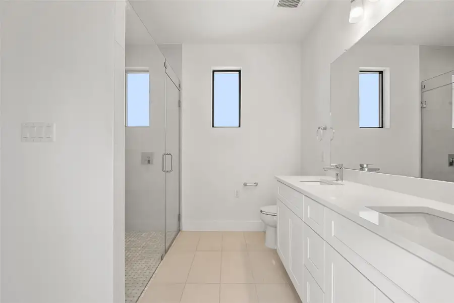 Full bathroom featuring double vanity, light tile patterned floors, and a stall shower