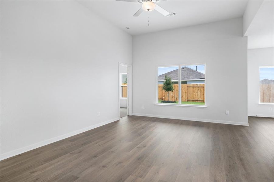 Spare room featuring dark wood-type flooring, a ceiling fan, and a high ceiling