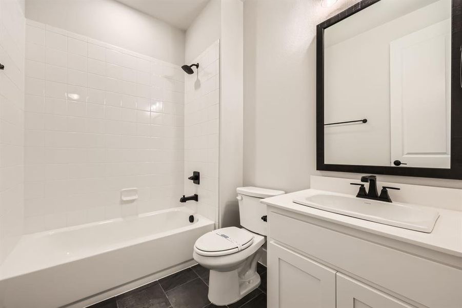 Full bathroom with toilet, tiled shower / bath combo, vanity, and tile patterned floors