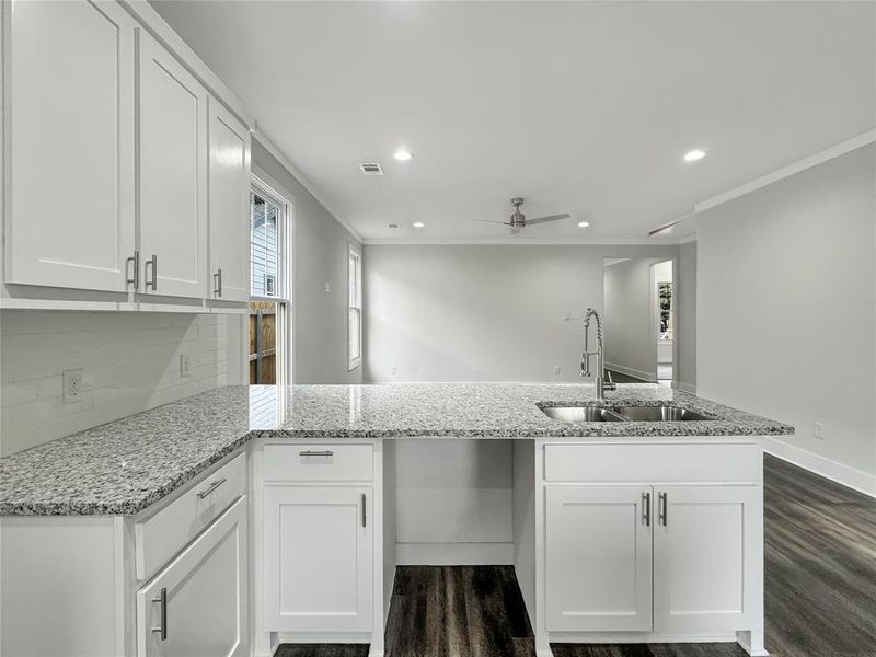 Kitchen featuring a peninsula, light stone counters, white cabinetry, recessed lighting, and a ceiling fan