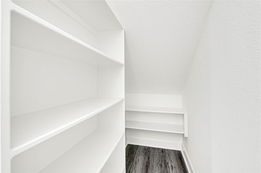 This photo shows a compact storage area with white built-in shelves and a slanted ceiling, featuring a modern, clean design and dark wood flooring. This photo shows a compact storage area with white built-in shelves and a slanted ceiling, featuring a modern, clean design and dark wood flooring.
