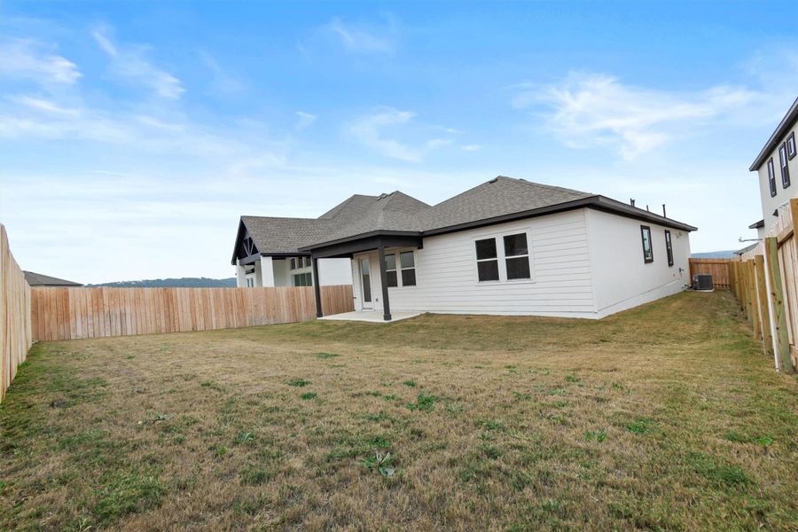 Back of house featuring central air condition unit and a yard