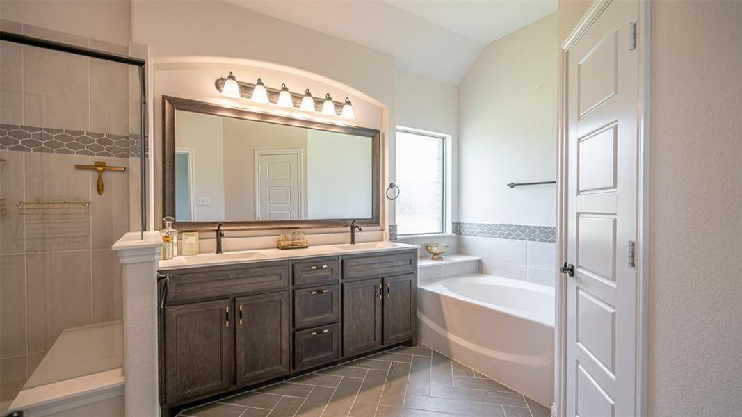 Spacious bathroom featuring a double vanity with dark wood-finish cabinetry, a large framed mirror, and a five-light fixture