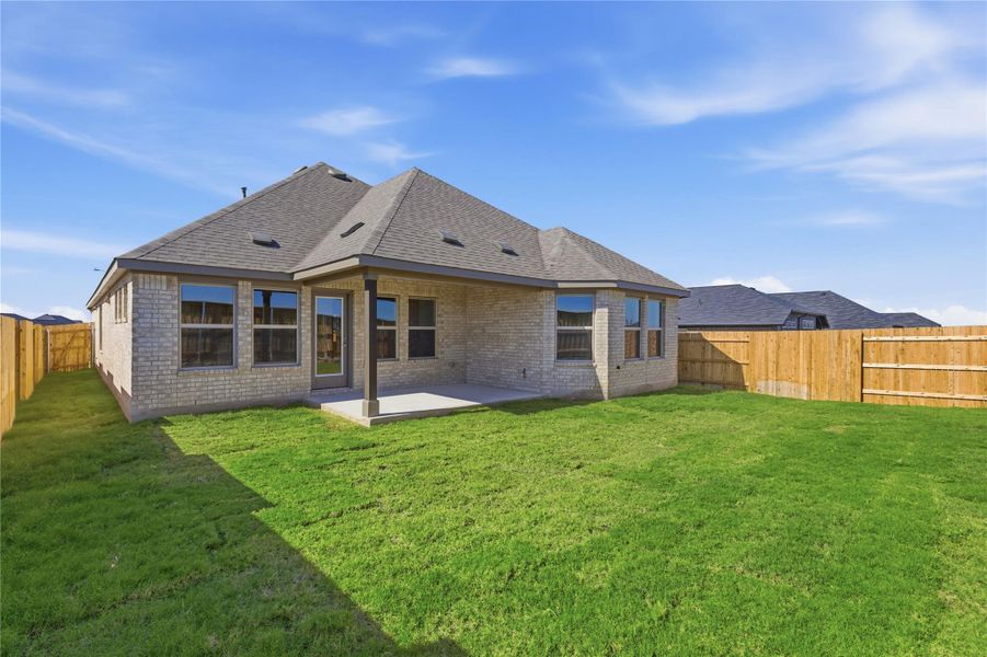 Back of property with brick siding, a shingled roof, a fenced backyard, and a patio