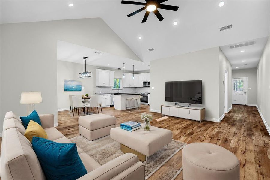 Living room featuring ceiling fan, high vaulted ceiling, and light hardwood / wood-style flooring