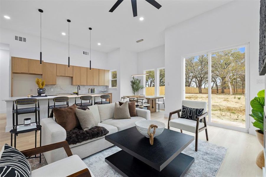 Living area with a towering ceiling, light wood-style flooring, recessed lighting, and a ceiling fan