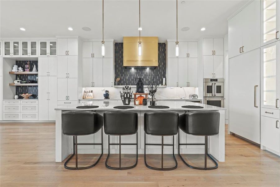 Kitchen with glass insert cabinets, a kitchen island with sink, white cabinetry, a breakfast bar, and recessed lighting Kitchen with glass insert cabinets, a kitchen island with sink, white cabinetry, a breakfast bar, and recessed lighting