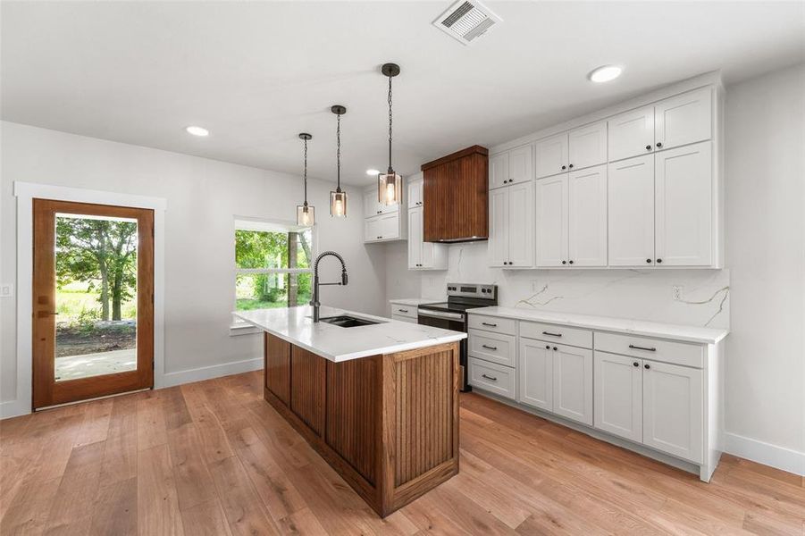 Kitchen featuring a central island with wood-finish paneling, white countertop, and pendant lighting