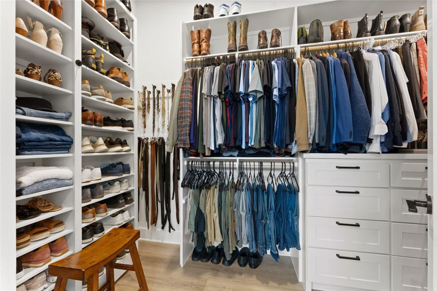 Built-in custom closet system featuring white cabinetry, multiple shelving units, hanging rods, and integrated drawers with dark hardware Built-in custom closet system featuring white cabinetry, multiple shelving units, hanging rods, and integrated drawers with dark hardware