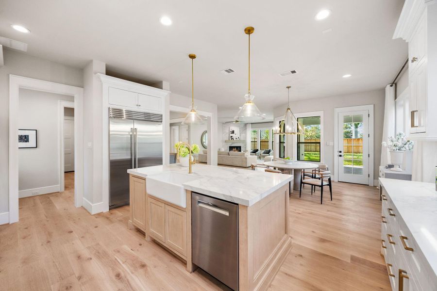 Kitchen view behind the Island. Stainless steel dishwasher w/ panel front trash compartment built into the island.
