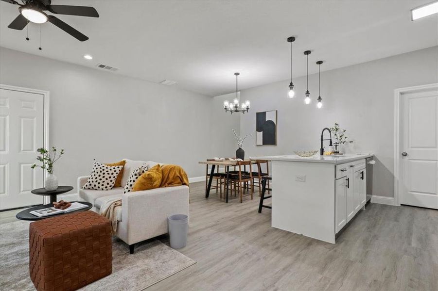 Living room featuring sink, ceiling fan with notable chandelier, and light wood-type flooring