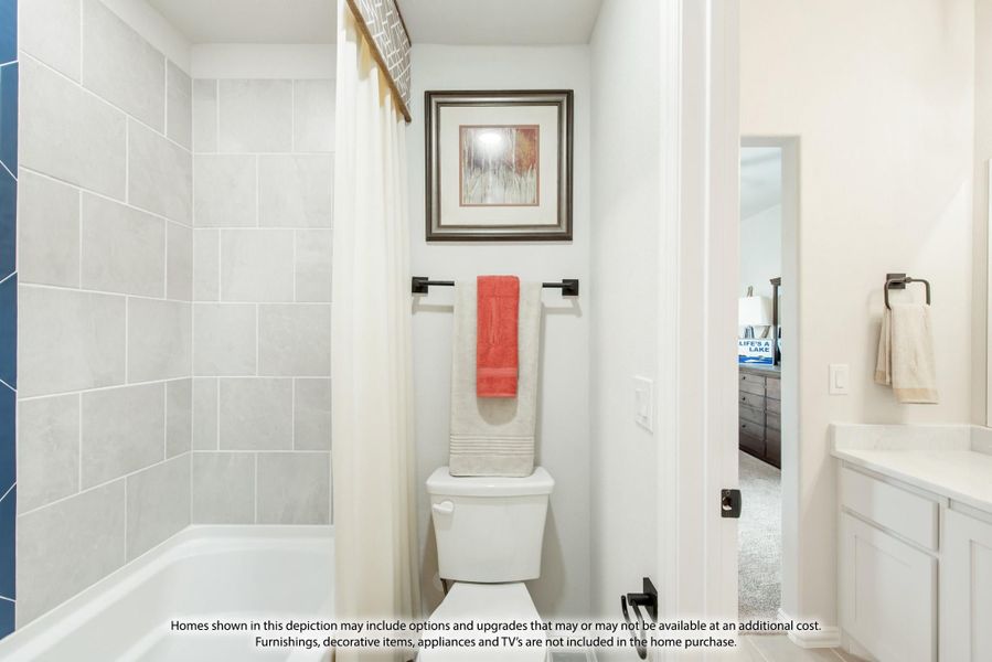 Bathroom with tiled shower-tub combo, toilet, and white vanity cabinet with neutral walls Bathroom with tiled shower-tub combo, toilet, and white vanity cabinet with neutral walls