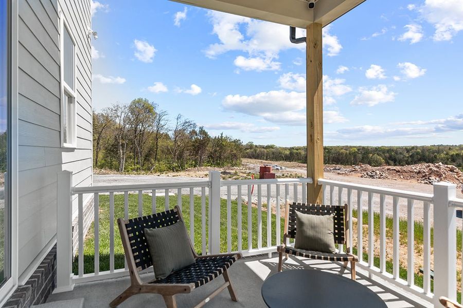 A deck with chairs and a table on it by a building.