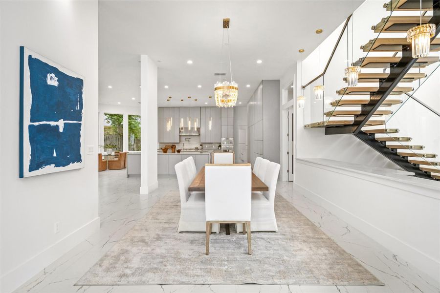 The elegant dining area, anchored by a stunning chandelier, serves as a sophisticated centerpiece between the kitchen and living room. The elegant dining area, anchored by a stunning chandelier, serves as a sophisticated centerpiece between the kitchen and living room.