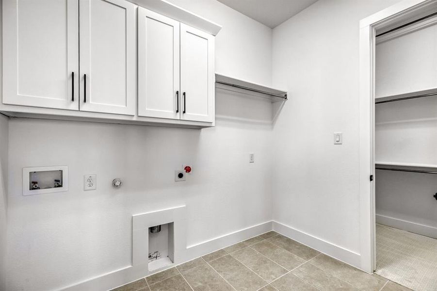 Laundry area with hookup for a gas dryer, washer hookup, electric dryer hookup, and cabinet space