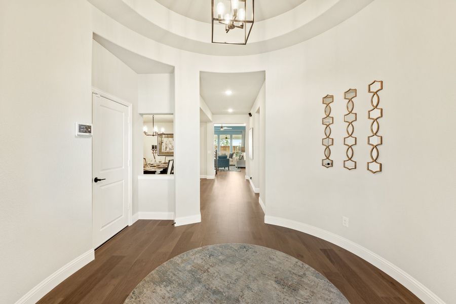 Rounded entryway foyer with dome ceiling, pendant chandelier, and dark hardwood floors leading to main living areas