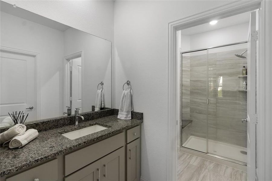 Bathroom featuring a single vanity with granite countertop, undermount sink, and chrome faucet
