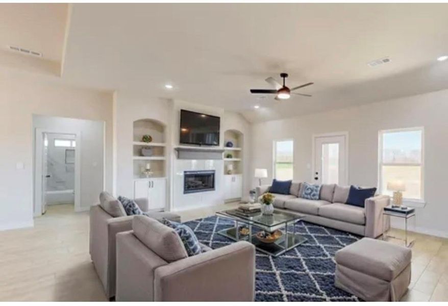 Living room featuring light wood-type flooring, built in features, a glass covered fireplace, a ceiling fan, and recessed lighting Living room featuring light wood-type flooring, built in features, a glass covered fireplace, a ceiling fan, and recessed lighting