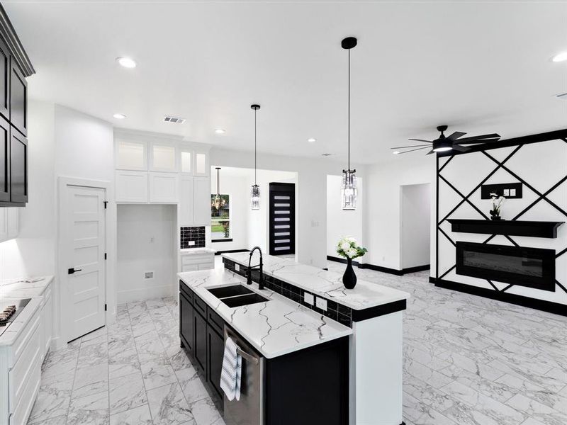 Open-concept living space featuring a kitchen island with dual sinks, pendant lighting, and marble-look tile flooring
