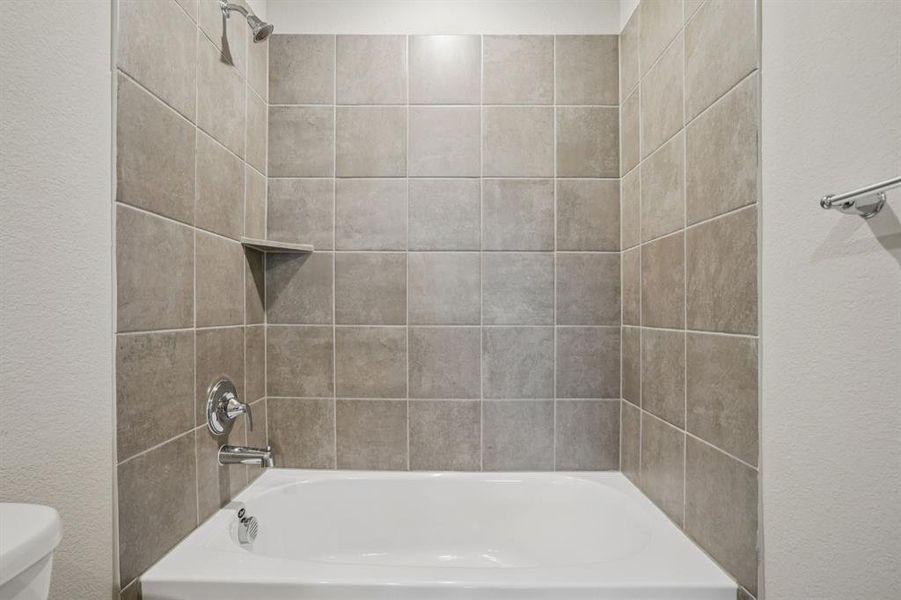 Bathroom featuring a textured wall and bathtub / shower combination