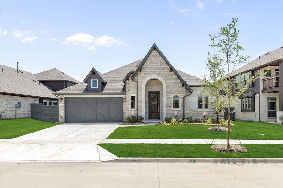 Single-story home with light stone exterior, arched entry, two-car garage, and manicured front lawn Single-story home with light stone exterior, arched entry, two-car garage, and manicured front lawn