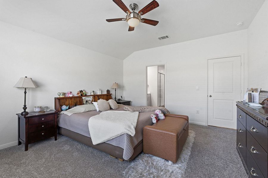 Bedroom with connected bathroom, dark carpet, a ceiling fan, and vaulted ceiling