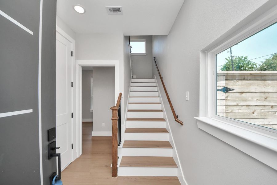 Welcoming front entry with modern finishes, warm wood accents, & convenient first-floor guest bedroom access for added flexibility & privacy.