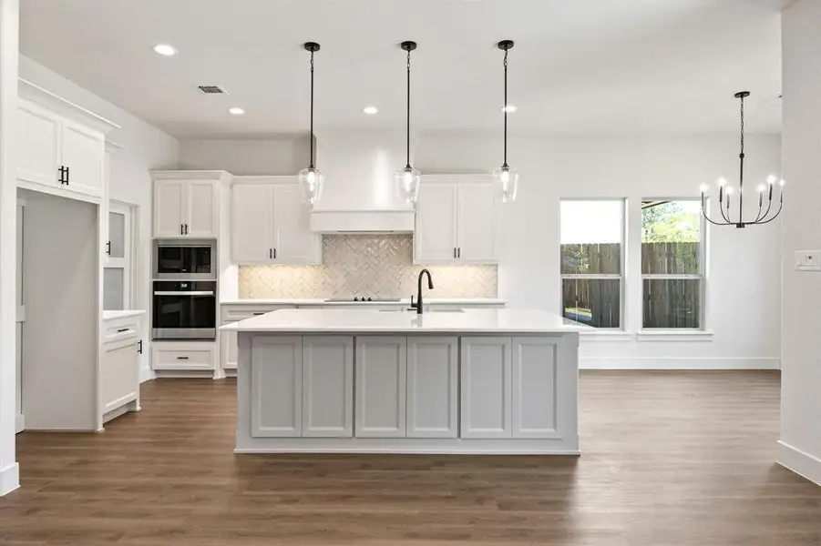Kitchen with a kitchen island with sink, white cabinets, stainless steel appliances, dark wood-type flooring, and decorative backsplash